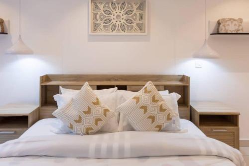 um quarto com uma cama com lençóis brancos e almofadas em Plush 1 Bedroom/Guest Washroom @The Lennox Airport em Acra