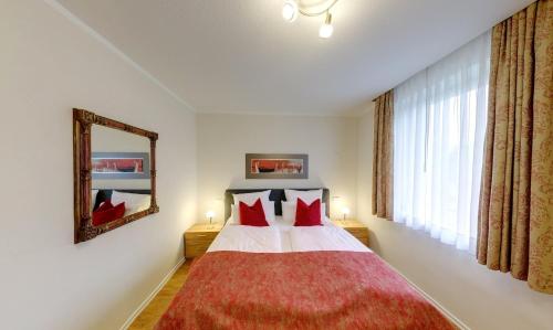a bedroom with a bed with red pillows and a mirror at Zur Windmühle Restaurant - Hotel in Beckum