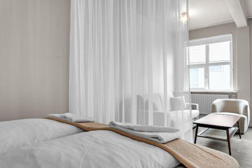 a white bedroom with two beds and a chair at The Swan House by Heimaleiga in Reykjavík
