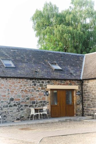 a stone building with a table and chairs in front of it at Traquair Arms Hotel in Innerleithen