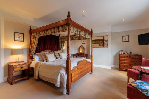 a bedroom with a four poster bed and a television at Blacksmiths Arms Inn in Scarborough