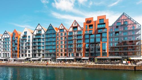 a row of buildings next to a body of water at Flatbook - City Center SPA Apartments Deo Plaza in Gdańsk