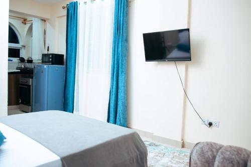 a room with a bed and a television on a wall at Semo's apartment in Bamburi