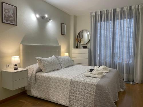 a bedroom with a white bed and a mirror at BierzINN apartamento in Ponferrada