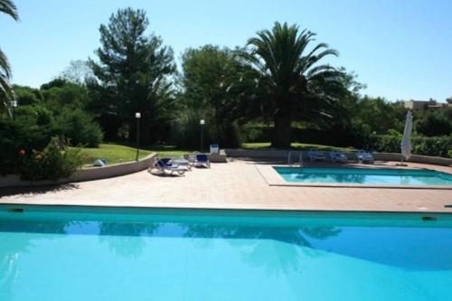 een groot zwembad met blauw water bij Villino Porto ottiolu in Porto Ottiolu