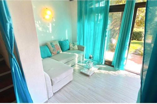 een woonkamer met een witte bank en blauwe gordijnen bij Villino Porto ottiolu in Porto Ottiolu
