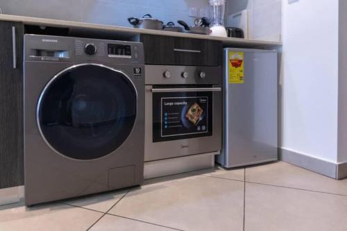 a kitchen with a washing machine and a dishwasher at Plush Studio @Embassy Gardens in Cantonments