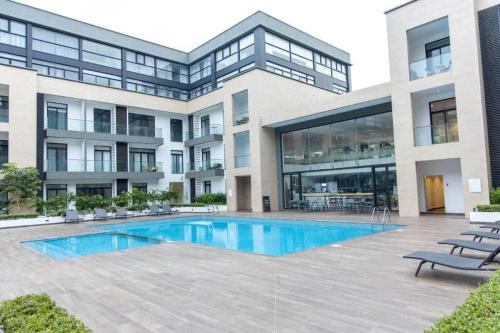 a large building with a swimming pool in front of it at Plush Studio @Embassy Gardens in Cantonments