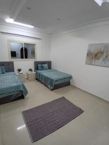 a white room with two beds and a rug at وحدة الأنس 3 in Al Madinah