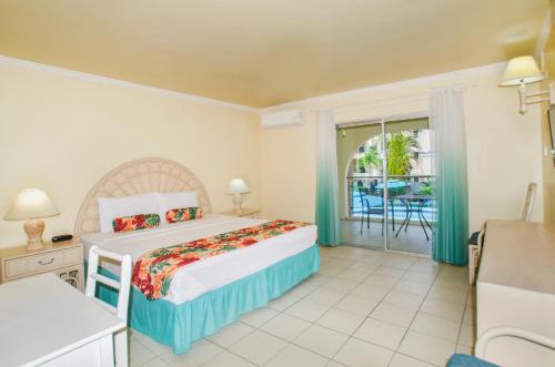 a bedroom with a bed and a balcony at Sunbay Hotel in Christ Church