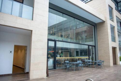 a large glass building with tables and chairs at Plush Studio @Embassy Gardens in Cantonments