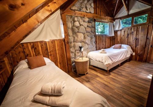 - une chambre avec 2 lits et un mur en pierre dans l'établissement Ruma Andina by DOT Cabana, à Villa La Angostura