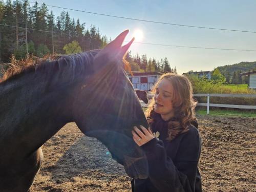 een vrouw die naast een zwart paard staat bij River Run Ranch - Telemark in Drangedal
