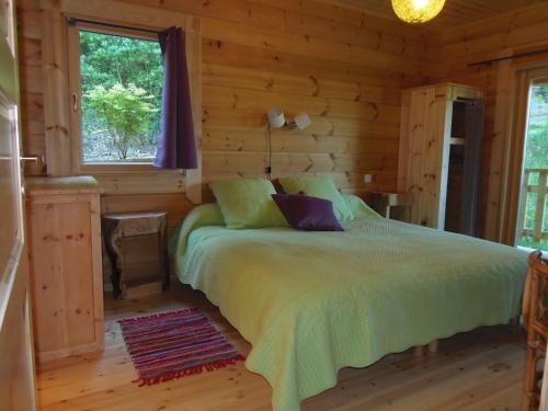 a bedroom with a bed in a log cabin at CHALET BOIS PLEINE NATURE 6 PLACES in Sainte-Eulalie-dʼOlt