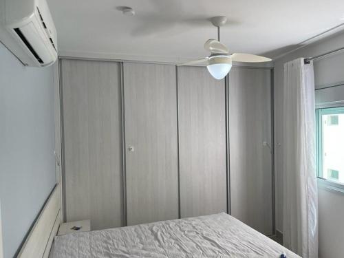 une chambre avec un lit et un ventilateur de plafond dans l'établissement Lindo Apto Guarujá 50m da Praia das Pitangueiras, à Guarujá