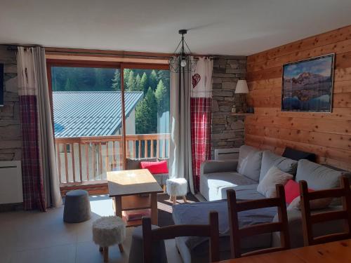 un salon avec un canapé et une grande fenêtre dans l'établissement Appartement chaleureux avec wifi de 10 personnes à Val-Cenis, à Lanslebourg-Mont-Cenis