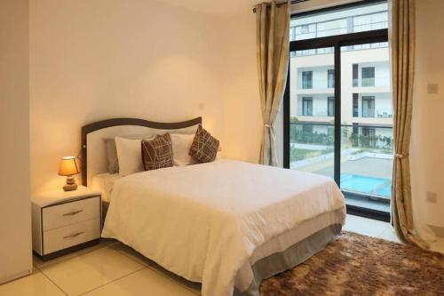 a bedroom with a bed and a large window at Pool View Apartment @Embassy Gardens in Cantonments