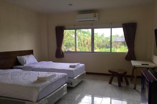 two beds in a room with a window at Be Fine Sabuy Hotel and Resort in Surat Thani