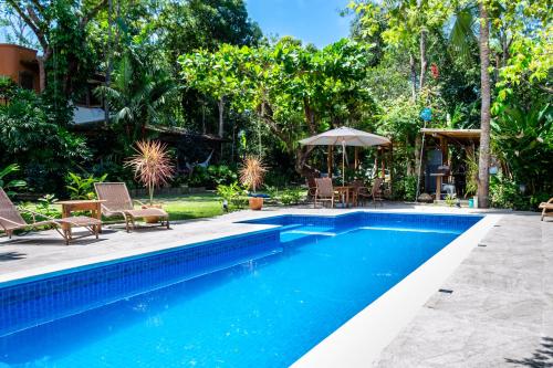 a pool with chairs and umbrellas in a yard at Casas Natureza Brasil in Arraial d'Ajuda