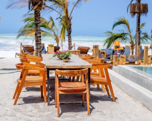 a wooden table and chairs on the beach at The Nest Boutique Resort in Paje