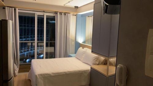 um quarto com uma cama branca e uma janela em Studio Moderno próximo ao Metrô em São Paulo