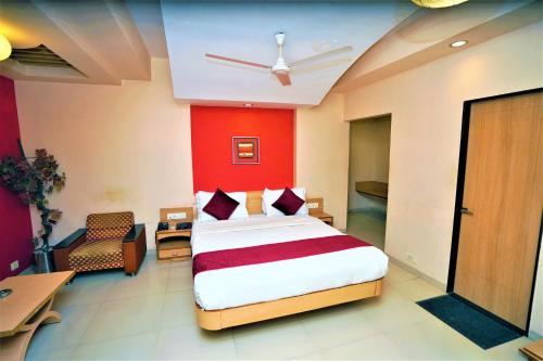 New Hotel Europa Inn في راجكوت: غرفة نوم بسرير وجدار احمر