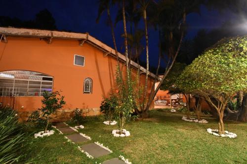 an orange house with trees in the yard at Pousada Casa Doce Vida in Águas de Lindóia