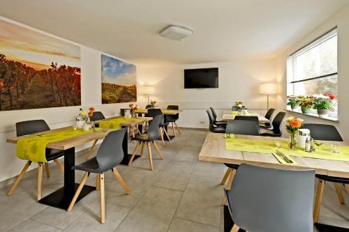 Vinotel Weinstrasse في Herxheim am Berg: مطعم مع طاولات وكراسي وتلفزيون بشاشة مسطحة