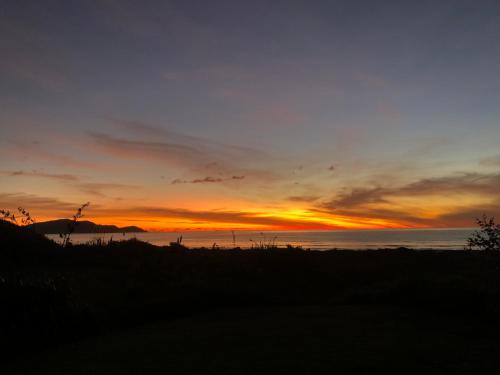 a sunset over the ocean with the sky at The Beachsider - Te Horo Beach Holiday Home in Te Horo