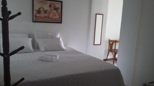 a bedroom with a white bed with a picture on the wall at hostel barra in Salvador