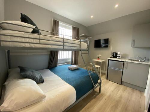 a bedroom with a bunk bed and a kitchen at Holloway Suites - Next To Emirates Stadium - Private Bathroom - Shared Kitchen in London