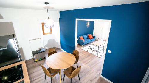 Cette chambre est dotée d'une table, de chaises et d'un mur bleu. dans l'établissement * Le Rétro : hyper centre*, à Luxeuil-les-Bains