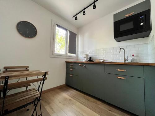 une cuisine avec des placards verts et une horloge murale dans l'établissement Studio Antigone, wifi, parking, TV, parking, à Montpellier