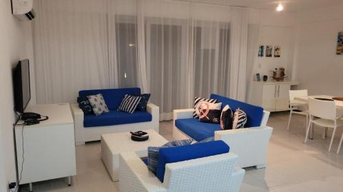 uma sala de estar com cadeiras azuis e brancas e uma mesa em Apartamento Particular de 03 suítes, Resort Treebies, Praia de Subauma - Ba em Entre Rios
