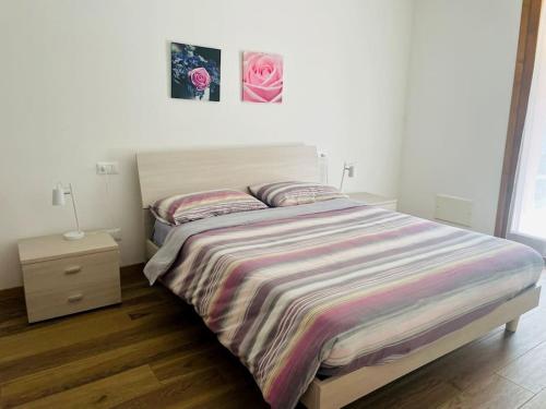 ein Schlafzimmer mit einem Bett mit gestreifter Tagesdecke und einem Nachttisch in der Unterkunft Casa di Nancy a Valdobbiadene 1(Unesco) in Valdobbiadene