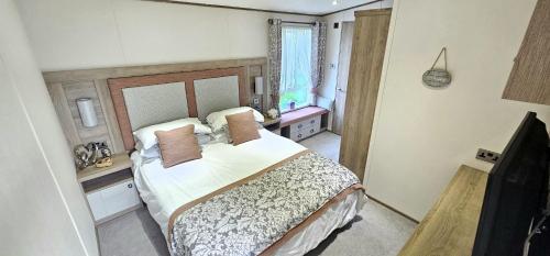 a bedroom with a large bed and a television at Hot Tub Lodge Cornwall - Meadow Lakes Holiday Park in St Austell