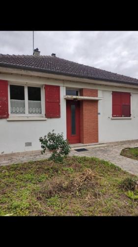 a white house with red shutters and a driveway at Maison Lison gare in Moon-sur-Elle