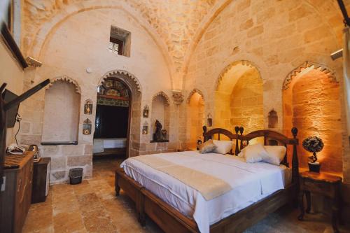 a bedroom with a large bed in a stone building at Hanedan Konağı Butik Otel Deluxe Triple Room with Turkish Bath Marvina in Mardin