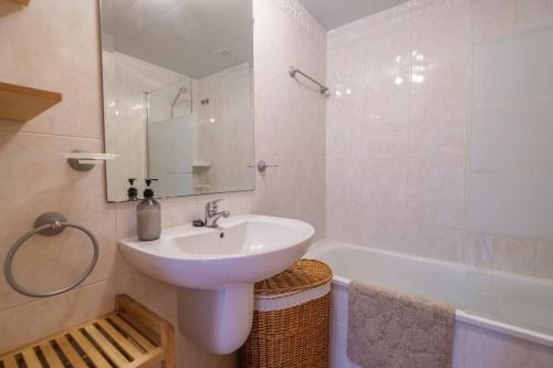 La salle de bains blanche est pourvue d'un lavabo et d'une baignoire. dans l'établissement Casa Gemma, à Alcanar
