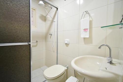 a white bathroom with a toilet and a sink at Pousada Casa Doce Vida in Águas de Lindóia