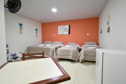 a room with three beds and a refrigerator at Pousada Casa Doce Vida in Águas de Lindóia