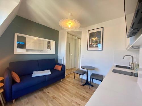 un salon avec un canapé bleu et une cuisine dans l'établissement STUDIO PARIS VUE IMPRENABLE, à Paris