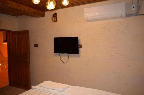 1 dormitorio con TV en la pared y 1 cama en Hasan Paşa Konuk Evi en Sanlıurfa