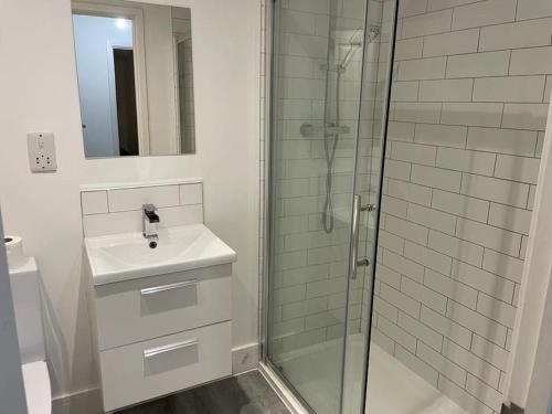 a white bathroom with a sink and a shower at Stunning and Spacious 2bed flat in central Woking in Woking
