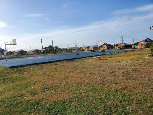 a long road with houses and a grass field at Beautiful 1-Bed House in New Harbour Village 3 Old Harbour St Catherine Jamaica Secured gated community in Old Harbour