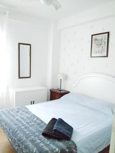 a bedroom with a white bed with a blue blanket at Apartamento luminoso y nuevo en Madrid Rio in Madrid