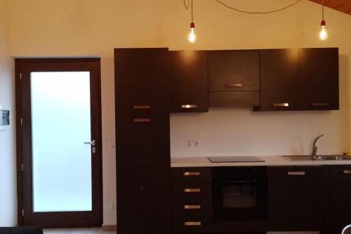 eine Küche mit schwarzen Schränken, einem Waschbecken und einer Tür in der Unterkunft Appartamento dei Tigli in Bra