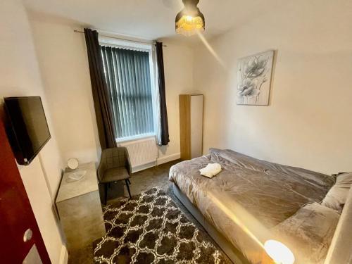 a bedroom with a bed and a tv and a window at Empire House in Burnley