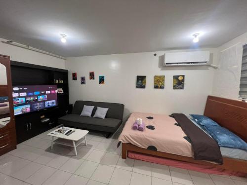 a bedroom with a bed and a couch and a flat screen tv at San Jose Residencias / enchanted kingdom / nuvali / slex / sta. rosa / paseo in Santa Rosa