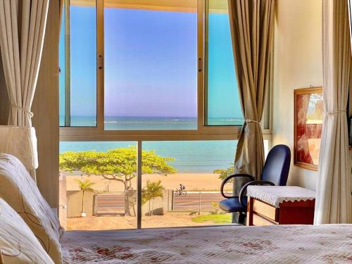 a bedroom with a view of the beach from a window at Frente Mar vista incrível Meaípe in Guarapari